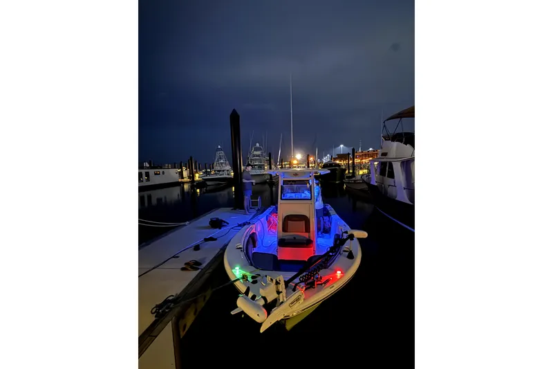 Slide: The Image of 2023 NauticStar 2602 Legacy boat illuminated at night in a marina. - 11