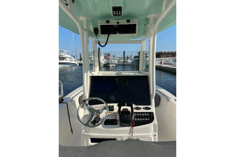 Slide: The Image of 2023 NauticStar 2602 Legacy boat dashboard with steering wheel and controls at marina. - 3