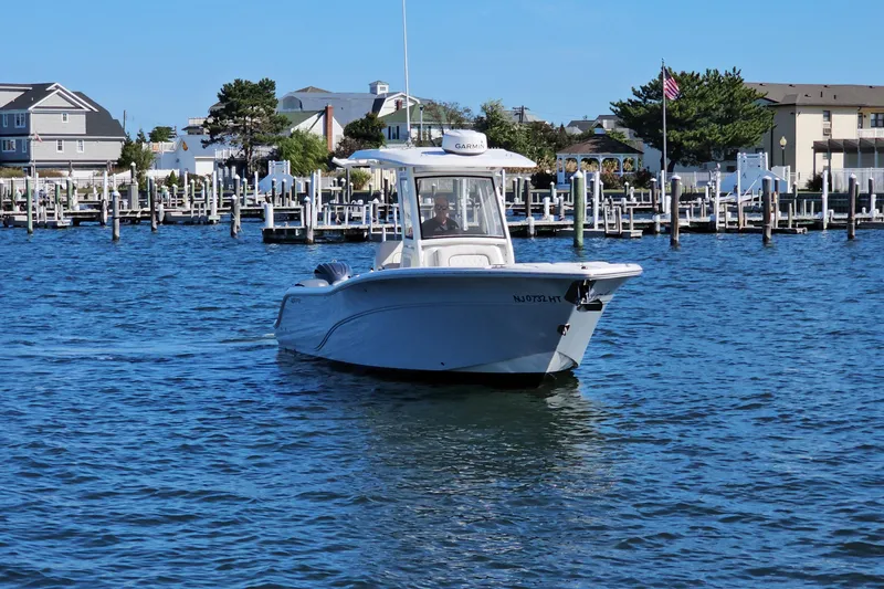 Slide: The Image of 2024 Sea Fox 268 Commander boat cruising in a marina with docks and buildings in the background. - 2
