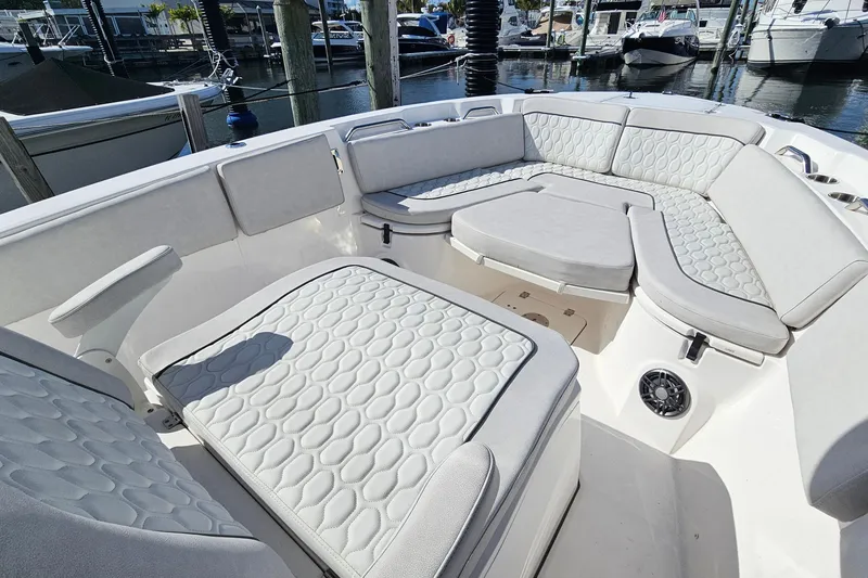 Slide: The Image of 2024 Sea Fox 268 Commander boat interior with cushioned seating in a marina setting. - 5