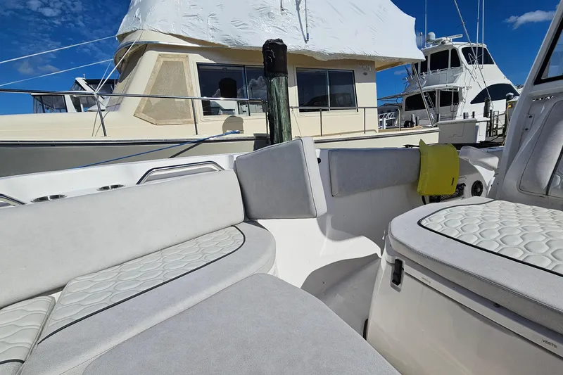 Slide: The Image of 2024 Sea Fox 268 Commander boat interior with cushioned seating, docked near other vessels. - 7