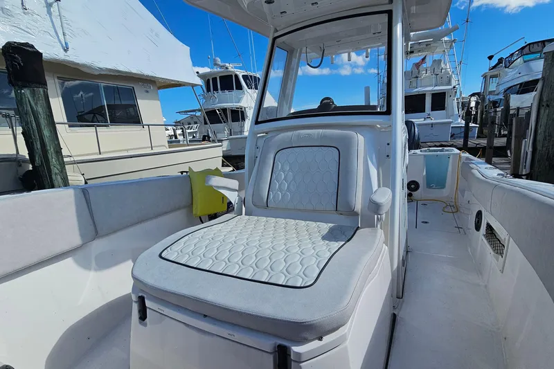 Slide: The Image of 2024 Sea Fox 268 Commander boat interior with cushioned seating at a marina. - 8