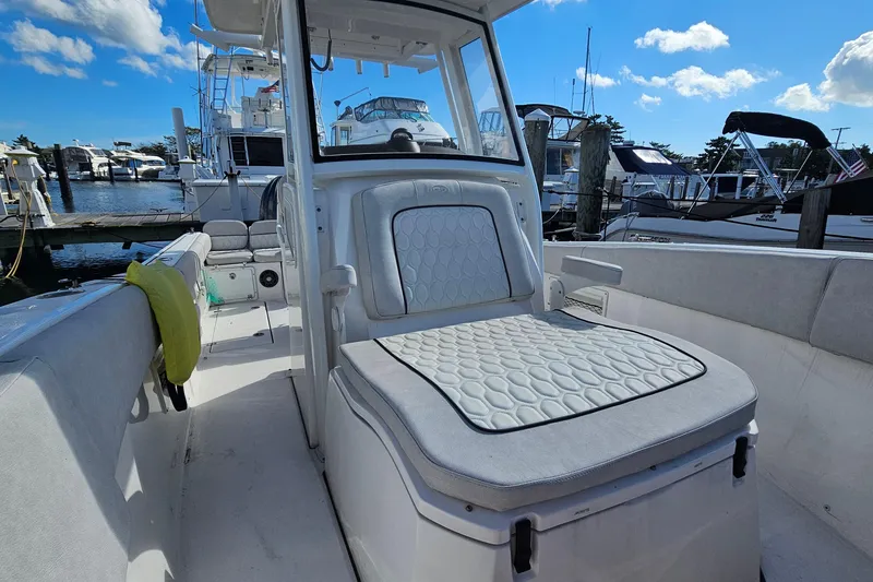 Slide: The Image of 2024 Sea Fox 268 Commander boat interior with cushioned seating at a marina. - 9