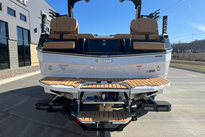 Slide: The Image of 2025 MasterCraft XT23 boat rear view with teak swim platform and tan seating. - 4