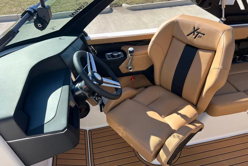 Slide: The Image of 2025 MasterCraft XT23 boat interior with tan leather seat and modern steering wheel. - 6