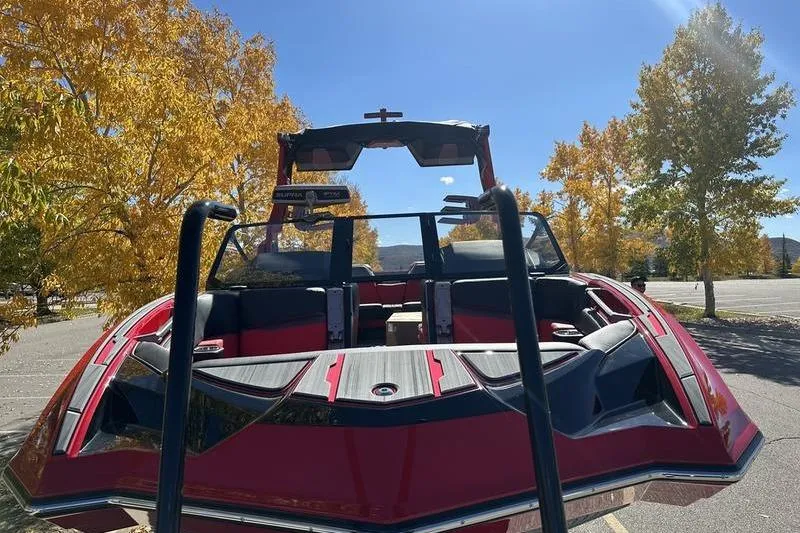 Slide: The Image of 2024 Supra SE 575 boat with vibrant red design, parked near autumn trees. - 10
