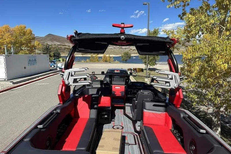 Slide: The Image of 2024 Supra SE 575 boat with red interior, parked near a scenic lake. - 5
