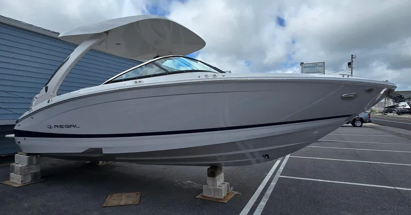 Slide: The Image of 2026 Regal LX6 boat displayed on blocks in a parking lot. - 15