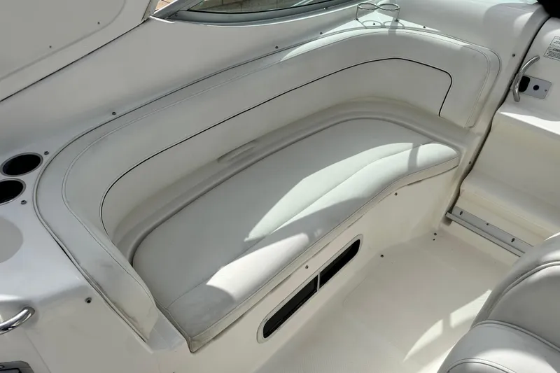 Slide: The Image of 2012 Bayliner 285 Cruiser interior seating area with cup holders and white upholstery. - 16