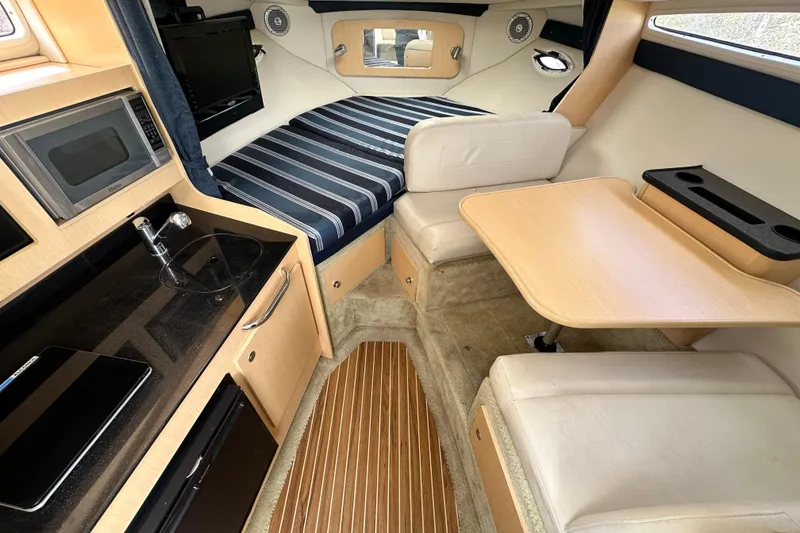 Slide: The Image of Interior of 2012 Bayliner 285 Cruiser with beige seating and wooden table. - 26