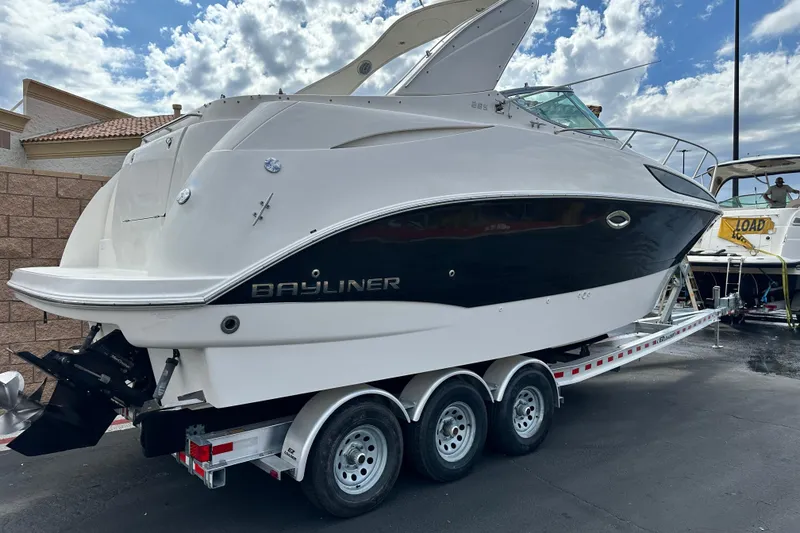 Slide: The Image of 2012 Bayliner 285 Cruiser on trailer, parked outdoors under cloudy sky. - 3