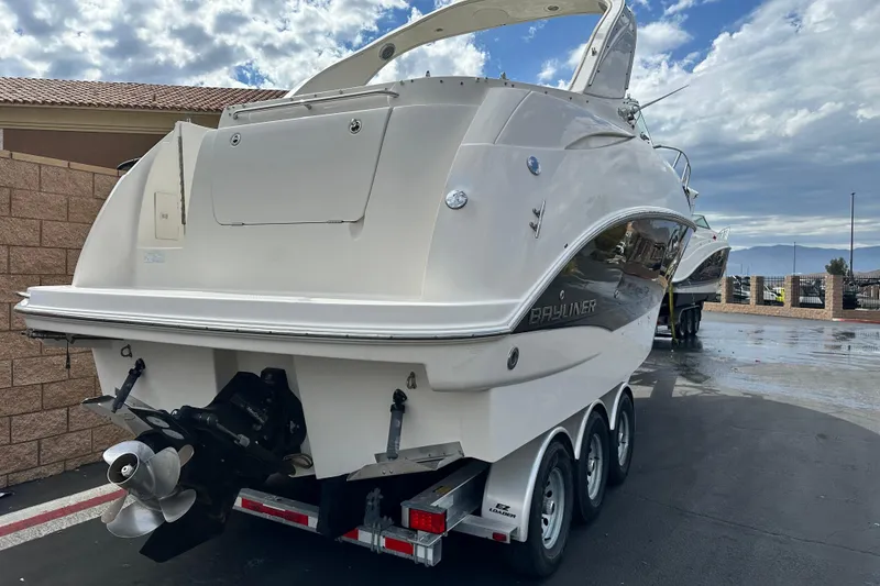Slide: The Image of 2012 Bayliner 285 Cruiser boat docked with mountainous backdrop under cloudy sky. - 4
