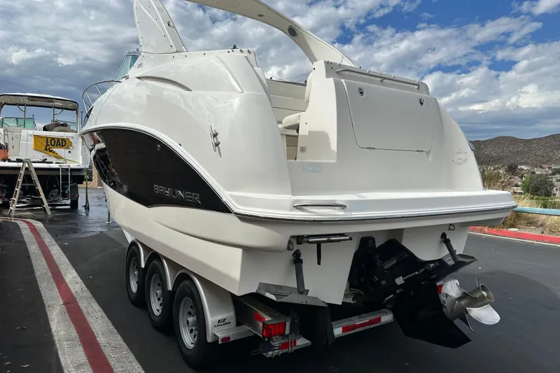 Slide: The Image of 2012 Bayliner 285 Cruiser boat rear view, parked on a trailer under cloudy skies. - 6