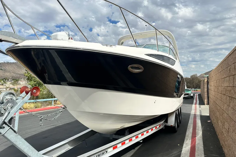 Slide: The Image of 2012 Bayliner 285 Cruiser on trailer, parked outdoors under a cloudy sky. - 7