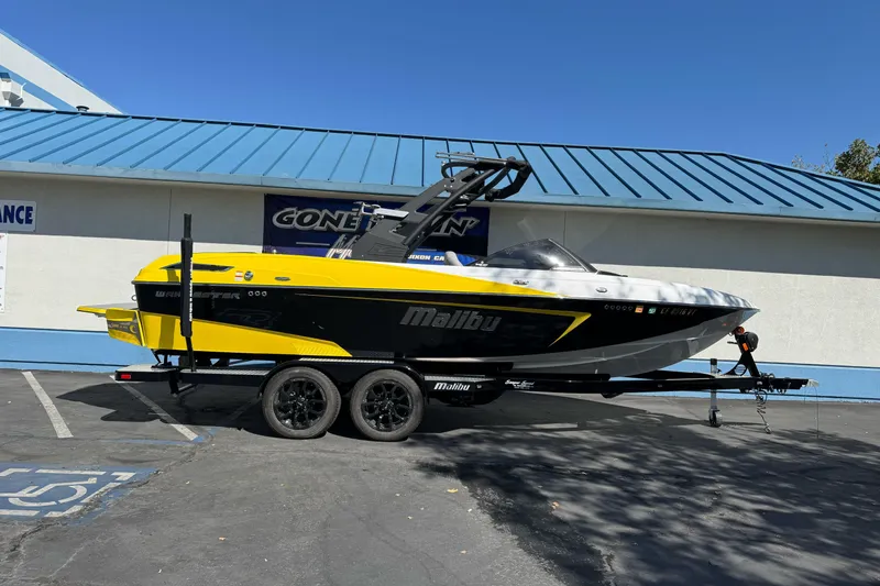 Slide: The Image of 2017 Malibu Wakesetter 23 LSV boat on trailer, yellow and black design, parked outdoors. - 0