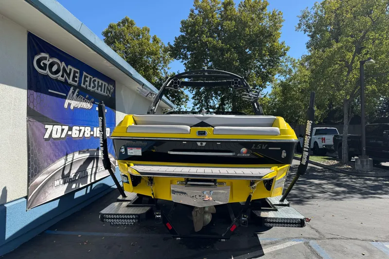 Slide: The Image of 2017 Malibu Wakesetter 23 LSV boat, yellow, parked outdoors near a "Gone Fishin'" sign. - 2