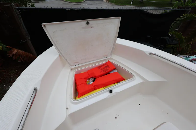 Slide: The Image of 2016 Robalo R160 Center Console boat with open storage compartment and life jackets. - 14