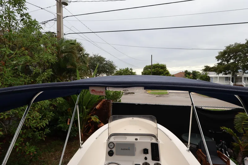 Slide: The Image of 2016 Robalo R160 Center Console boat with blue Sunbrella canopy, surrounded by greenery. - 25
