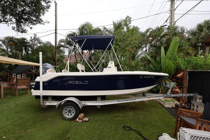 Slide: The Image of 2016 Robalo R160 Center Console boat on trailer, surrounded by lush greenery. - 44
