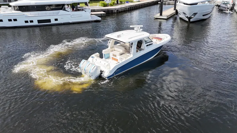 Slide: The Image of 2020 Boston Whaler 350 Realm cruising in marina, surrounded by yachts. - 19
