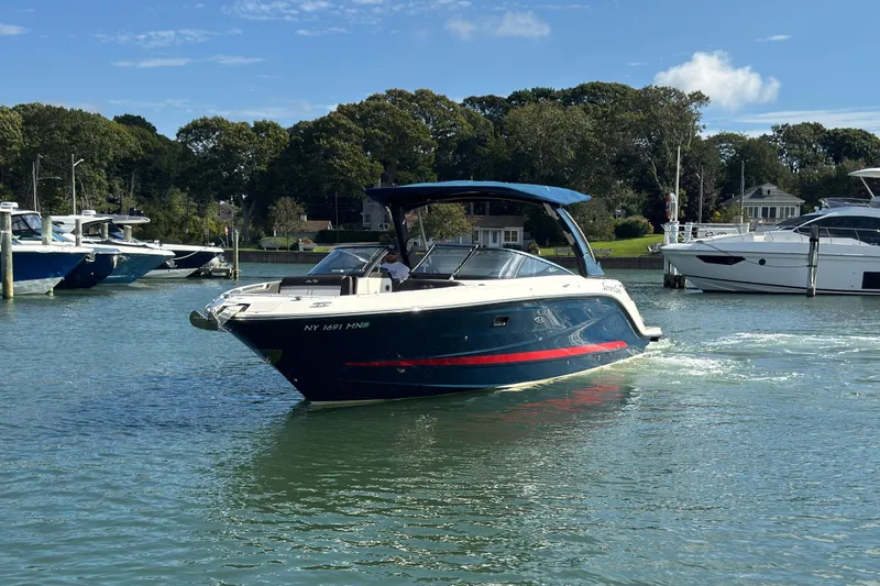Slide: The Image of 2017 Sea Ray SLX 310 Outboard cruising on a serene lake with lush greenery. - 2