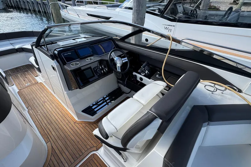 Slide: The Image of 2017 Sea Ray SLX 310 Outboard boat interior with sleek dashboard and wooden flooring. - 20