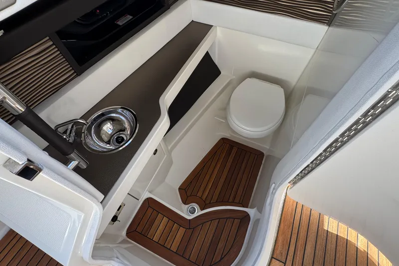 Slide: The Image of 2017 Sea Ray SLX 310 Outboard boat interior with sink, toilet, and wooden flooring. - 26