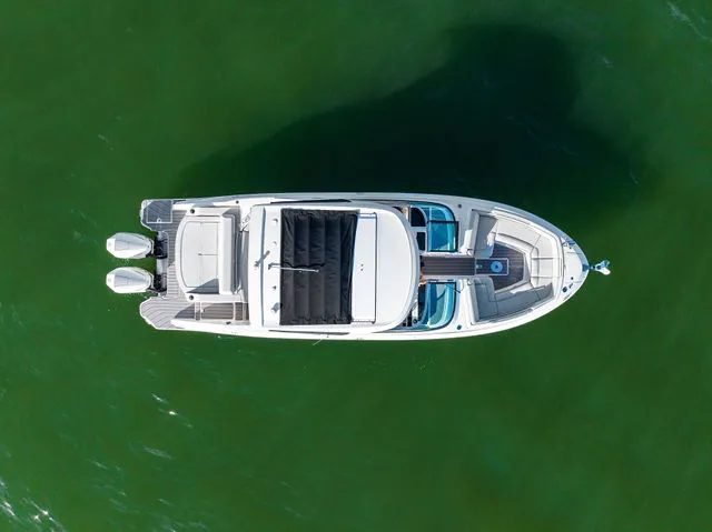 Slide: The Image of 2017 Sea Ray SLX 310 Outboard boat with spacious seating, docked near wooden buildings. - 45