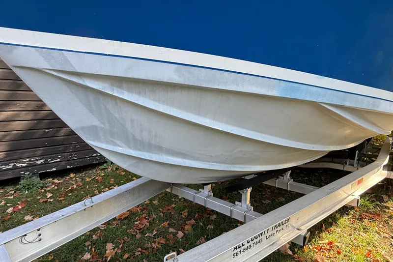 Slide: The Image of 1965 Bertram boat hull on trailer, blue and white design, parked on grass. - 15