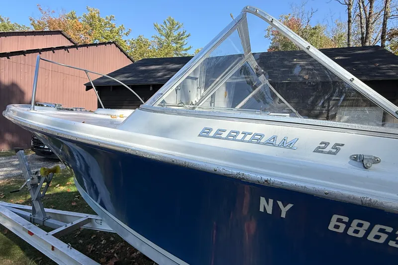 Slide: The Image of 1965 Bertram boat on trailer, blue and white, parked near wooden building. - 21