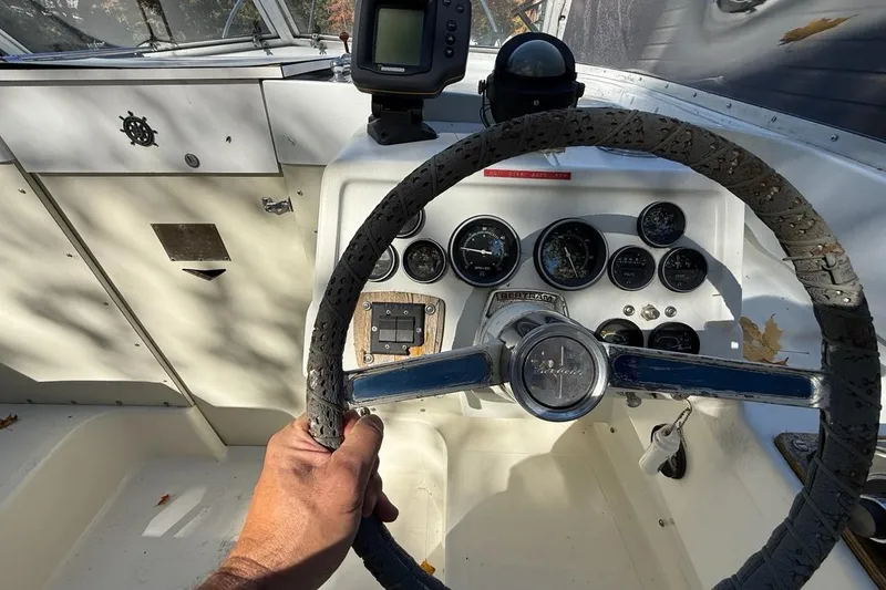 Slide: The Image of Steering wheel and dashboard of a 1965 Bertram boat, featuring gauges and controls. - 22