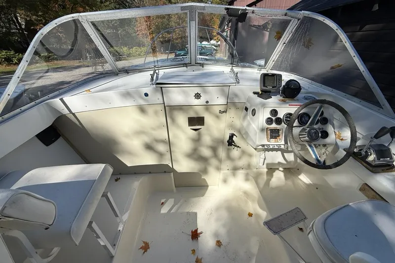 Slide: The Image of 1965 Bertram boat cockpit with steering wheel, gauges, and autumn leaves scattered. - 27