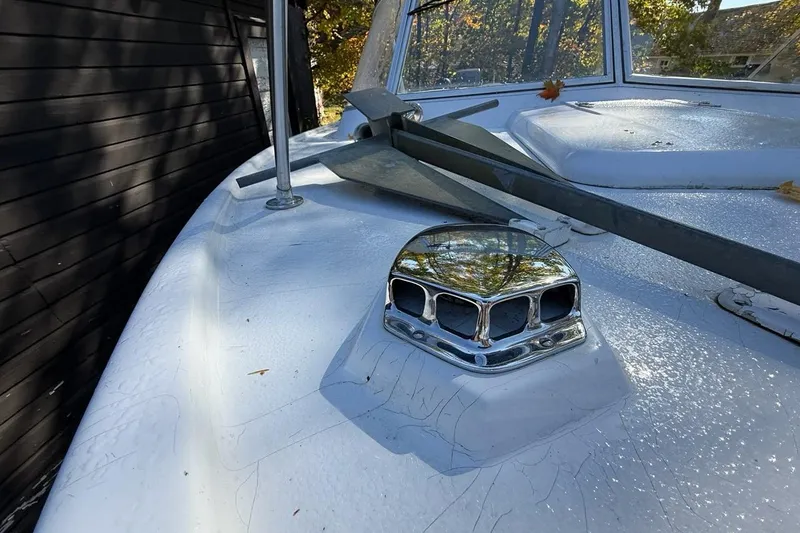 Slide: The Image of 1965 Bertram boat deck with chrome vent and windshield, surrounded by autumn leaves. - 32