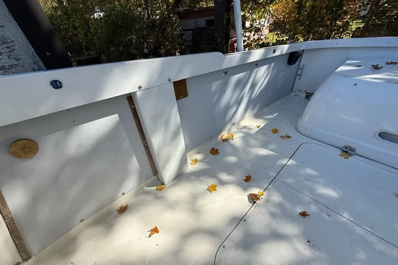 Slide: The Image of 1965 Bertram boat deck with scattered autumn leaves, surrounded by trees. - 44