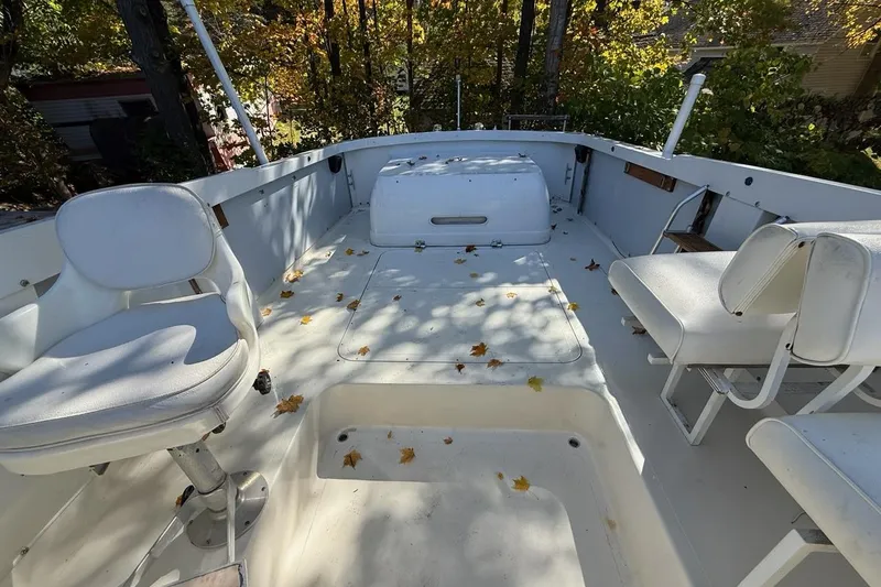 Slide: The Image of 1965 Bertram boat deck with white seating, scattered autumn leaves, surrounded by trees. - 45