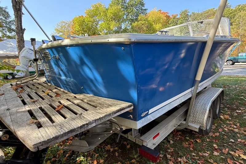 Slide: The Image of 1965 Bertram boat on trailer, blue hull, autumn leaves, outdoor setting. - 68
