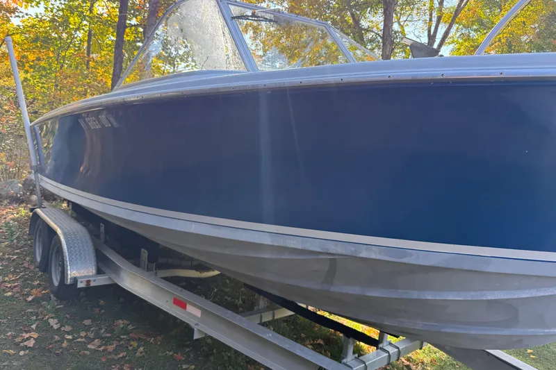 Slide: The Image of 1965 Bertram boat on trailer, blue hull, parked outdoors with autumn foliage. - 7
