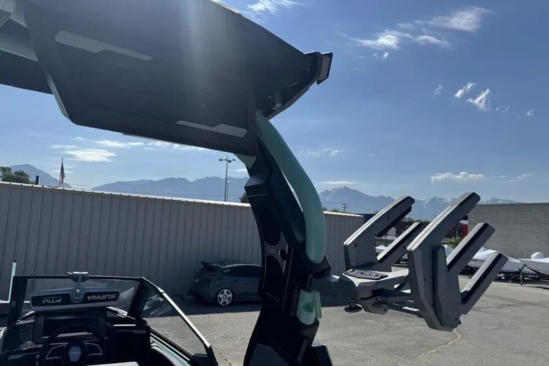 Slide: The Image of 2024 Supra SE 575 boat with advanced wakeboard tower in a sunny outdoor setting. - 11