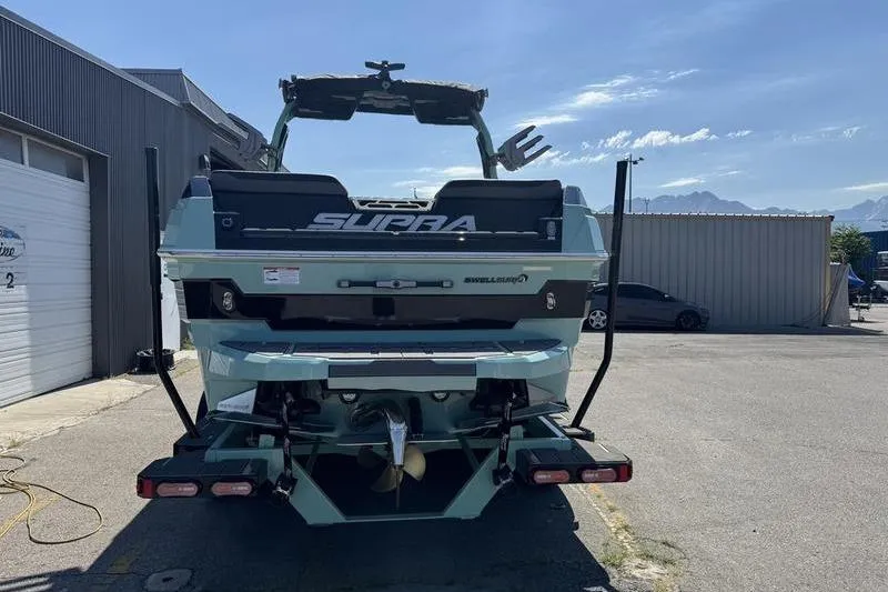 Slide: The Image of 2024 Supra SE 575 boat rear view in a sunny outdoor setting. - 2