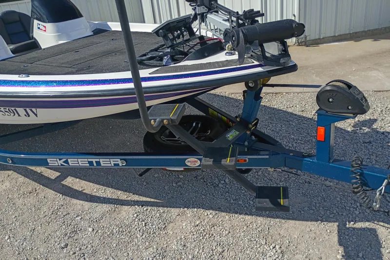 Slide: The Image of 2003 Skeeter TZX190 boat on trailer, parked on gravel near a metal building. - 6