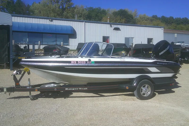 The Image of 2009 Ranger 1850 Reata boat on trailer, parked outside dealership, with Mercury outboard motor. - 1