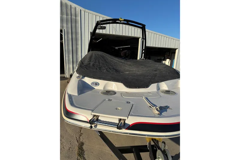 Slide: The Image of 2014 Tahoe 215 Xi boat with cover, parked outside a metal building. - 21