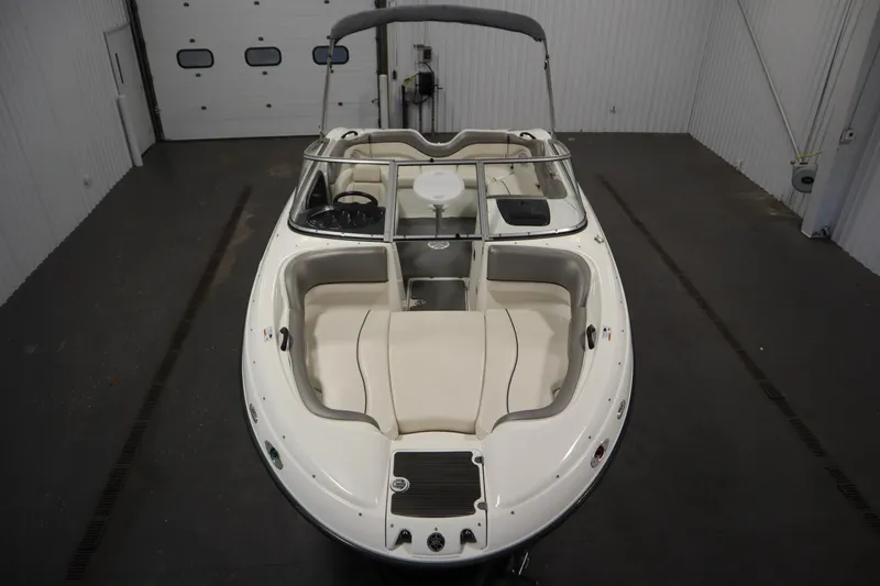 Slide: The Image of 2010 Yamaha 210 SX boat in indoor storage, showcasing sleek design and spacious seating. - 9