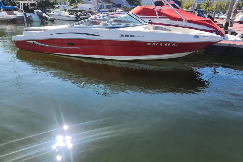 Slide: The Image of 2008 Sea Ray 205 Sport boat docked on calm water, reflecting sunlight. - 7