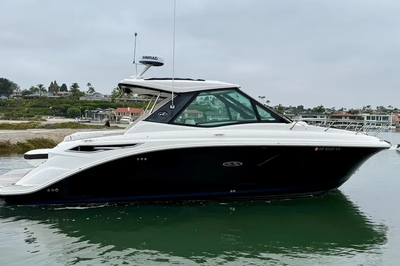Slide: The Image of 2023 Sea Ray Sundancer 320 Coupe yacht on calm water, coastal background. - 15
