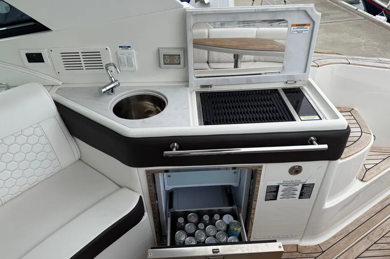 Slide: The Image of 2023 Sea Ray Sundancer 320 Coupe boat interior with kitchenette and seating area. - 30