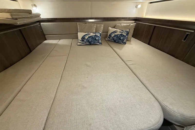 Slide: The Image of 2023 Sea Ray Sundancer 320 Coupe interior cabin with beige seating and decorative pillows. - 58