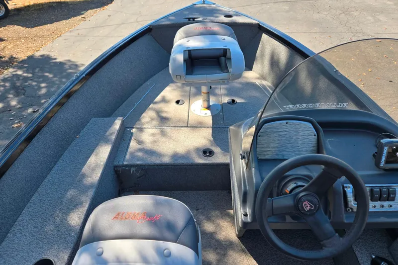 Slide: The Image of 2018 Alumacraft Escape 165 CS boat interior with steering wheel and seating. - 12
