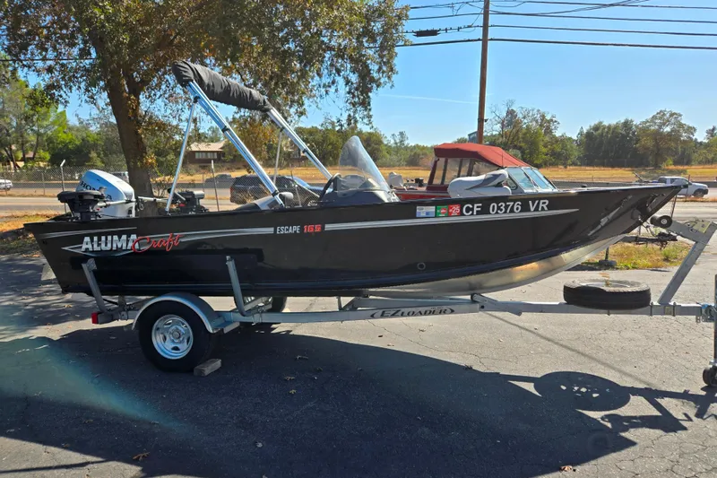 Slide: The Image of 2018 Alumacraft Escape 165 CS boat on trailer, parked outdoors. - 13