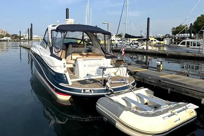 Slide: The Image of 2014 Four Winns V375 boat docked with inflatable dinghy, marina background. - 2